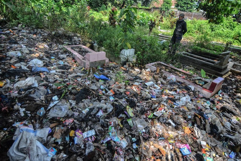 Warga menyaksikan tumpukan sampah yang menimbun makam warga di Kampung Nagrog, Kota Tasikmalaya, Jawa Barat, Selasa (23/4/2019).