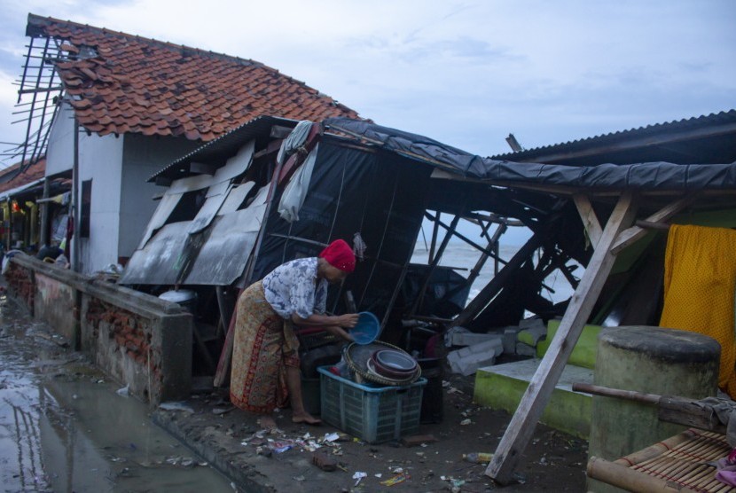 Warga merapihkan perabotan di rumahnya yang ambruk akibat abrasi di Desa Cemara Jaya, Karawang, Jawa Barat.