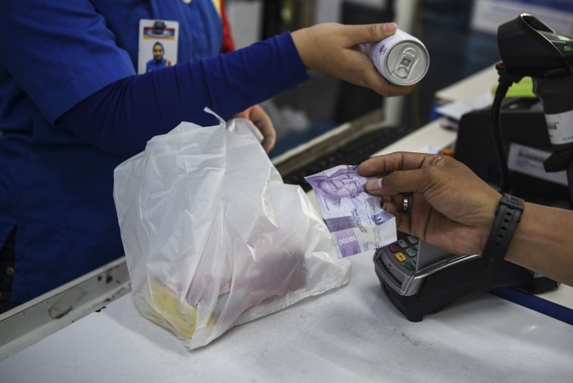 Kasir memberikan barang milik pembeli di salah satu toko ritel di Jakarta, Jumat (27/4/2019).