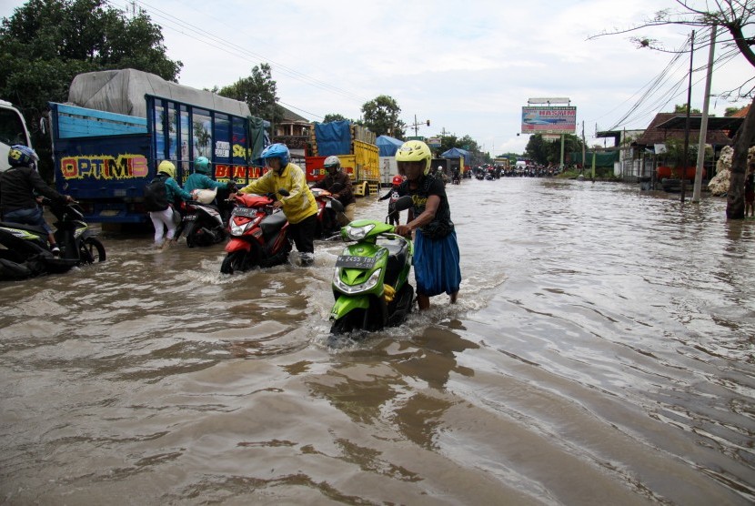 Warga mendoroang kendaraan bermotor yang mogok akibat banjir yang menggenangi kawasan Jalan Raya Pantura Kraton, Pasuruan, Jawa Timur. Jalan di wilayah Kraton Pasuruan sepanjang 1,5 kilometer ditutup karena banjir. Ilustrasi.