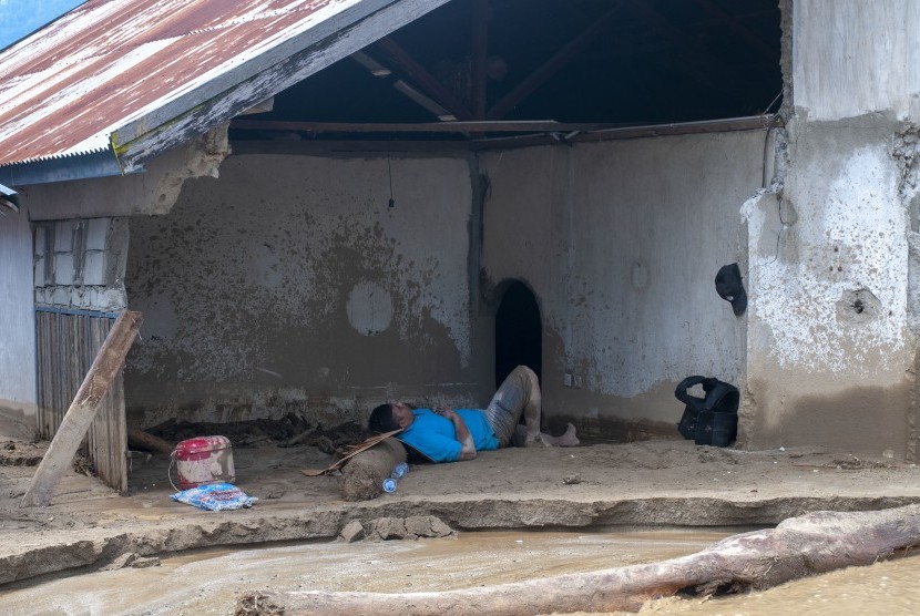 Seorang warga korban banjir bandang tertidur di timbunan lumpur di rumahnya di Desa Bangga, Dolo Selatan, Sigi, Sulawesi Tengah, Senin (29/4/2019). 