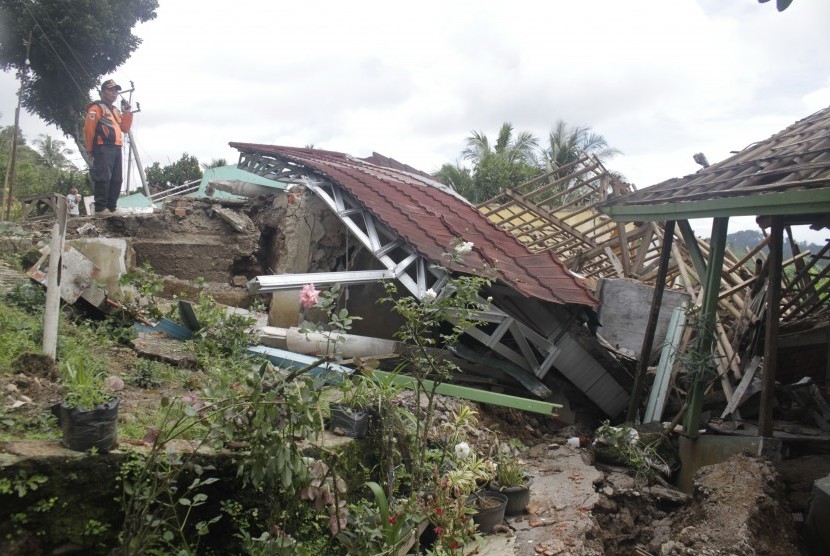 Petugas Badan Penanggulangan Bencana Daerah (BPBD) mengamati salah satu rumah rusak terdampak bencana gerakan tanah di Desa Kertaangsana, Kecamatan Nyalindung, Sukabumi, Jawa Barat, Kamis (2/5/2019).