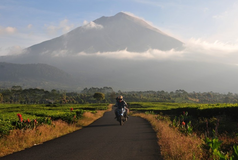 Pengendara melintasi Kayu Aro Barat dengan latar Gunung Kerinci, Jambi, Jumat (3/5/2019). 