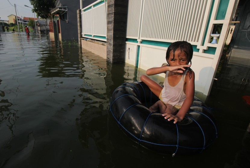 Seorang anak bermain air banjir di kawasan Kelurahan Sumberejo, Kecamatan Pakal, Surabaya, Jawa Timur, Jumat (3/5/2019).