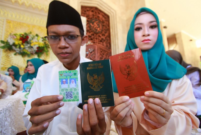 Pasangan pengantin menunjukkan buku nikah dan kartu nikah usai mengikuti acara nikah massal di Masjid Raya Sabilal Muhtadin, Banjarmasin, Kalimantan Selatan, Sabtu (4/5/2019).