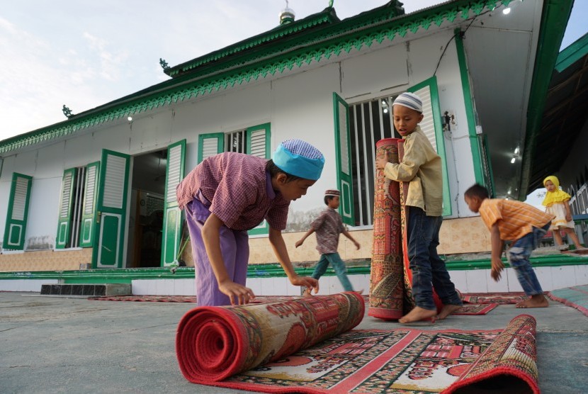 Sejumlah anak menyiapkan tempat berbuka puasa di Situs Cagar Budaya Masjid Al Amin atau biasa dikenal Masjid Tua Wani di Desa Wani, Kabupaten Donggala, Sulawesi Tengah, Jumat (10/5/2019). 