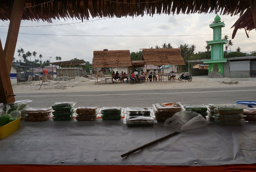 Sejumlah warga korban bencana gempa dan tsunami berjualan menu berbuka puasa (takjil) pada lapak yang didirikan disekitar rumah mereka yang rata dengan tanah di Mamboro, Palu, Sulawesi Tengah, Selasa (14/5/2019).