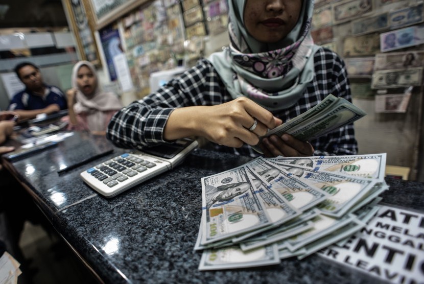 Seorang petuga menghitung mata uang dolar AS di salah satu gerai penukaran mata uang asing di Jakarta, Rabu (15/5/2019).