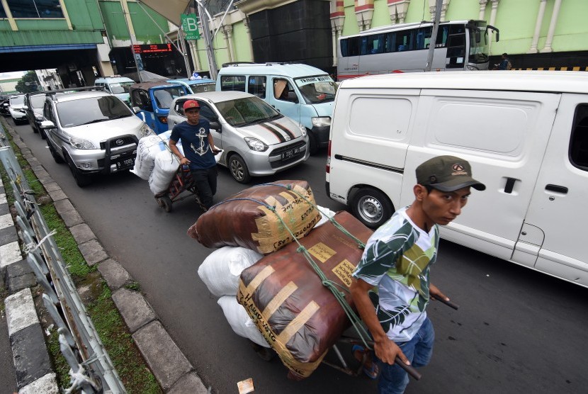 Kuli angkut melintas di antara kendaraan bermotor yang terjebak kemacetan di kawasan Pasar Tanah Abang, Jakarta, Rabu (15/5/2019). 