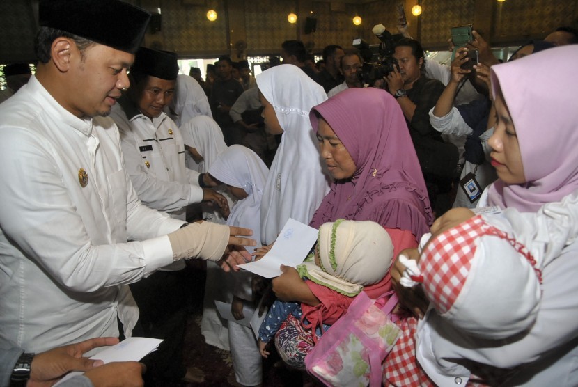 Wali Kota Bogor Bima Arya (kiri) bersama Wakil Gubernur Jawa Barat UU Ruzhanul Ulum (tengah) menyerahkan santunan saat Safari Ramadhan 1440 H di Masjid Agung Al-Mi'raj, Kota Bogor, Jawa Barat, Kamis (16/5/2019).