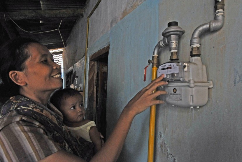 Ibu rumah tangga memperhatikan meter ukur sambungan jaringan gas PT PGN (Perusahaan Gas Negara).