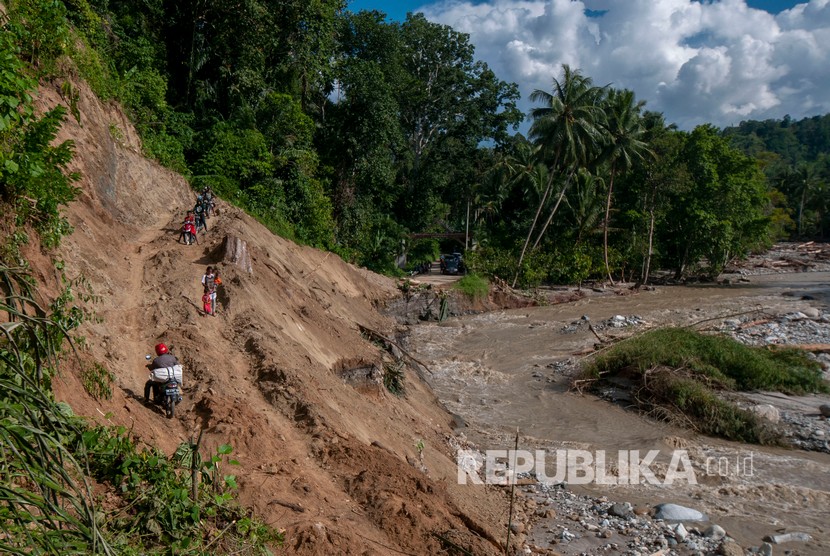 Warga melintasi tebing gunung akibat jalan utama Trans Palu-Kulawi terputus diterjang banjir di Desa Salua, Kecamatan Gumbasa, Sigi, Sulawesi Tengah, Ahad (19/5/2019).  