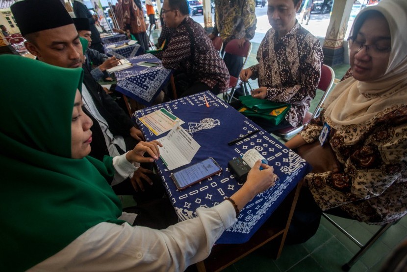 Petugas melayani warga yang berzakat dengan aplikasi Simba saat pelayanan zakat mal. 