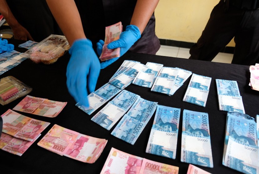 Polisi menunjukkan barang bukti uang kertas palsu saat gelar perkara uang palsu. (Dok)