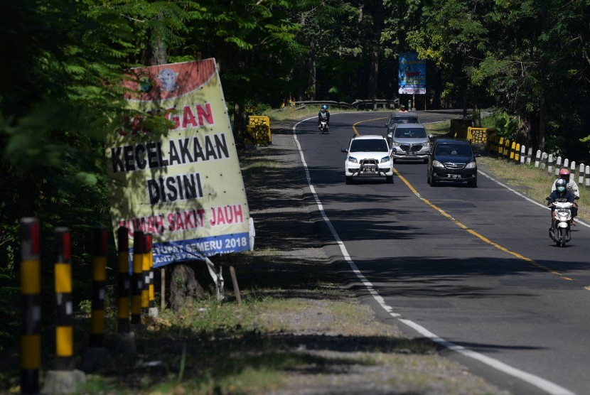 Pengendara mobil dan motor melintas di dekat spanduk himbauan hati-hati berkendara di Jalan Raya Ngawi-Solo, Ngawi, Jawa Timur, Sabtu (1/6/2019). 
