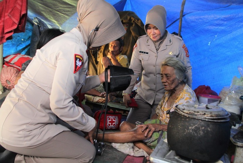 Dua orang tim medis dari Brimob Polda Sulawesi Tenggara memeriksa kesehatan lansia korban banjir bandang di tenda pengungsian di Kelurahan Wanggu, Kendari, Sulawesi Tenggara, Senin (10/6/2019).