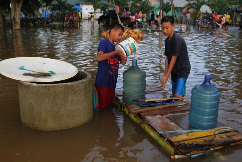 Warga mengambil air di sumur yang telah bercampur air banjir di Desa Wanuamandala, Konawe, Sulawesi Tenggara, Sabtu (15/6/2019).