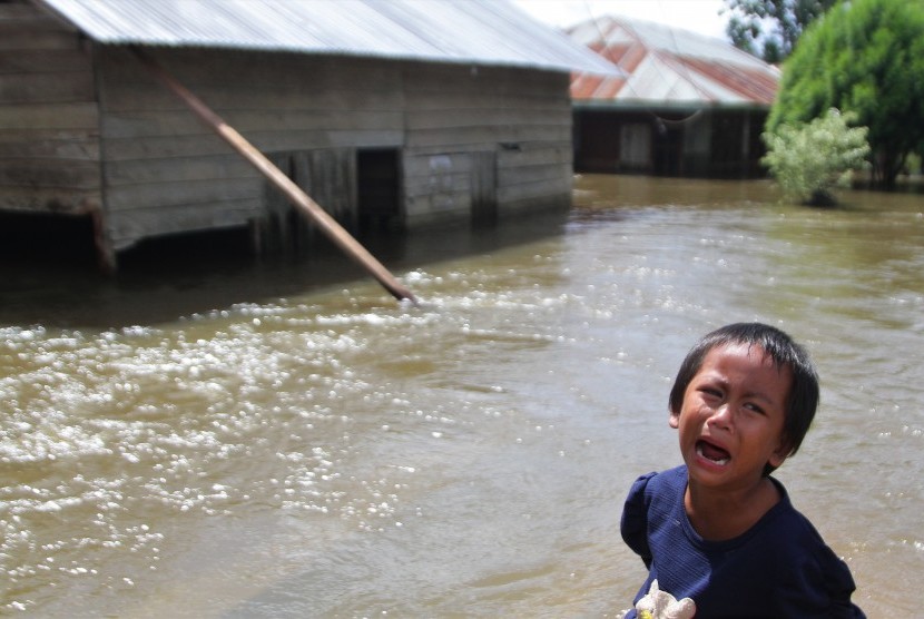 Seorang anak menangis di depan rumahnya yang terendam banjir di Desa Laikandonga, Konawe Selatan, Sulawesi Tenggara, Senin (17/6/2019).