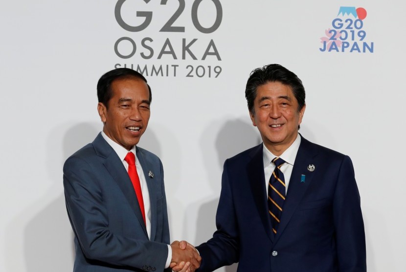 Presiden Joko Widodo (kiri) disambut PM Jepang Shinzo Abe pada KTT G-20 di Osaka, Jepang, Jumat (28/06).