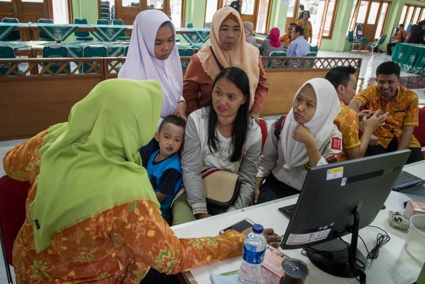 Siswa dan wali murid berkonsultasi dengan petugas pusat layanan informasi Penerimaan Peserta Didik Baru (PPDB) di SMA 7 Solo, Jawa Tengah, Selasa (2/7/2019).