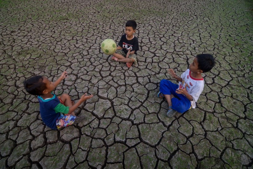 Sejumlah anak memanfaatkan areal persawahan yang terdampak kekeringan untuk bermain bola di Cibiru Hilir, Kabupaten Bandung, Jawa Barat, Rabu (3/7/2019).