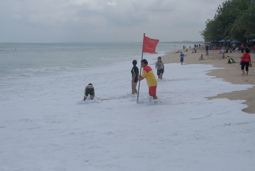 Anggota Badan Penyelamat Wisata Tirta (Balawista) memasang bendera larangan berenang saat terjadinya gelombang pasang di Pantai Kuta, Badung, Bali.