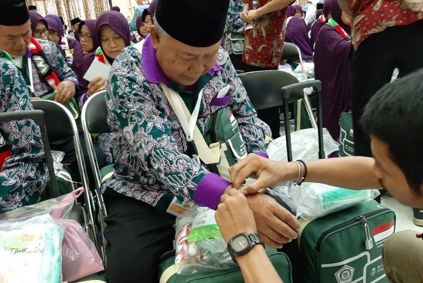Petugas sedang memasangkan gelang identitas pada salah seorang Jamaah Calon Haji Kloter 1 dari Kabupaten Bogor di Asrama Haji Embarkasi Jakarta-Bekasi, Kota Bekasi, Sabtu (6/7).