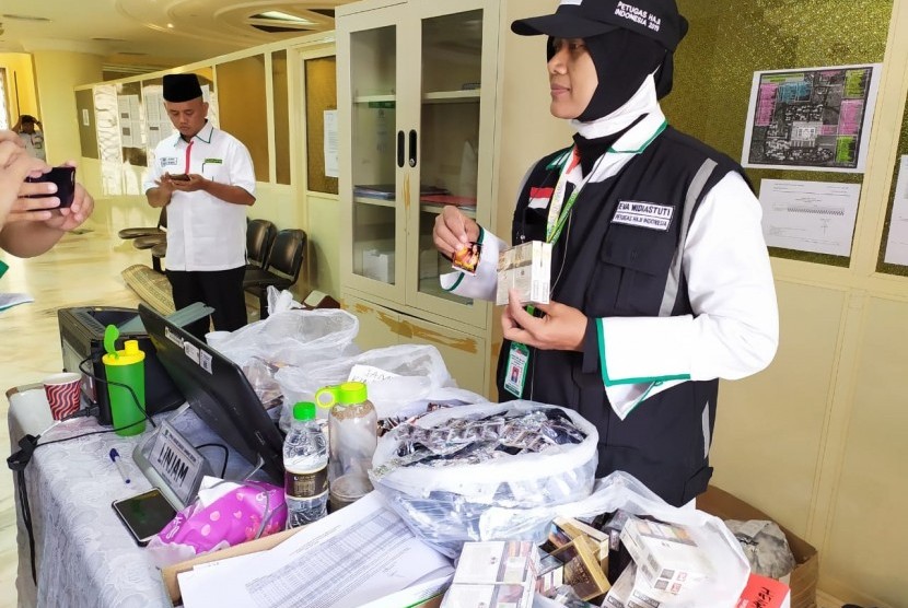 Petugas Perlindungan Jamaah (Linjam) Eva Widiastuti, menunjukkan sejumlah barang yang disita dari jamaah haji asal Embarkasi Surabaya, Jumat (12/7). Barang-barang yang disita antara lain, rokok, jamu kuat, sari rapet, dan lainnya. 