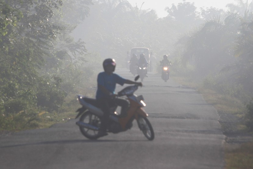 Sejumlah pengendara menembus kabut asap yang menutupi kawasan jalan di Desa Suak Nie, Kecamatan Johan Pahlawan, Aceh Barat, Senin (15/7/2019).