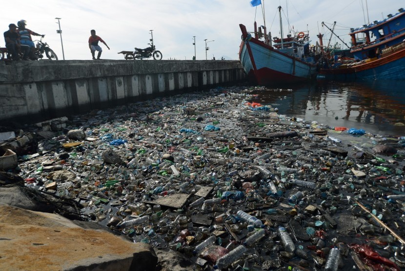 Kapal nelayan bersandar dekat tumpukan sampah botol plastik bekas bercampur minyak solar di Pelabuhan Perikanan Samudera, Lampulo, Banda Aceh, Aceh Senin (15/7/2019). 