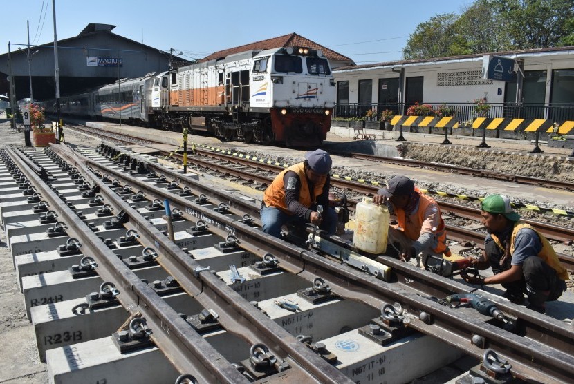 Pekerja memasang rel pada bantalan saat pembangunan jalur ganda kereta api (KA) lintas selatan di kawasan Stasiun KA Madiun, Jawa Timur, Rabu (17/7/2019). 