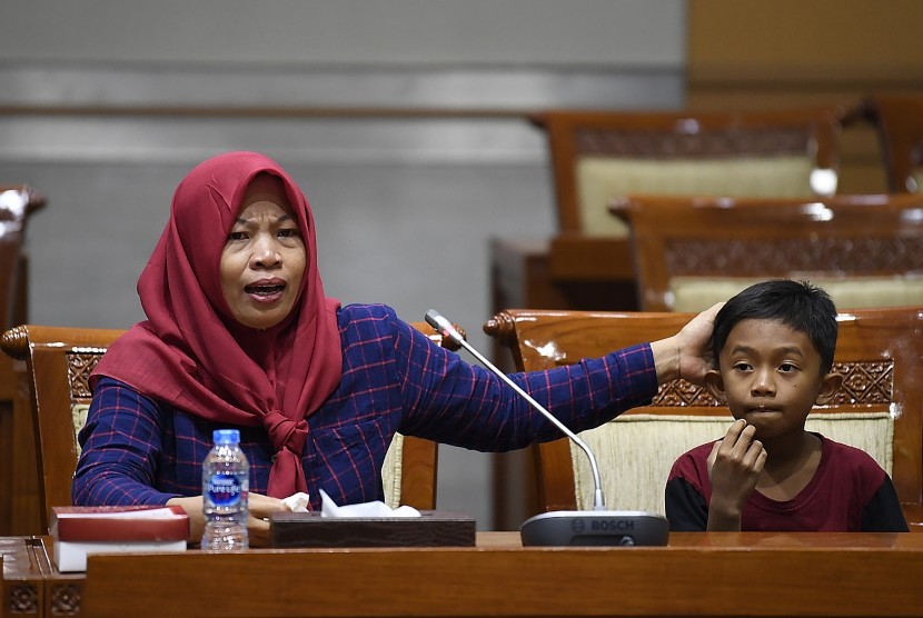 Terpidana kasus pelanggaran Undang-Undang Transaksi dan Informasi Elektronik (UU ITE), Baiq Nuril Maknun (kiri) didampingi anaknya menyampaikan tanggapan saat rapat pleno Komisi III DPR terkait surat persetujuan amnesti di Kompleks Parlemen Senayan, Jakarta, Selasa (23/7/2019). 