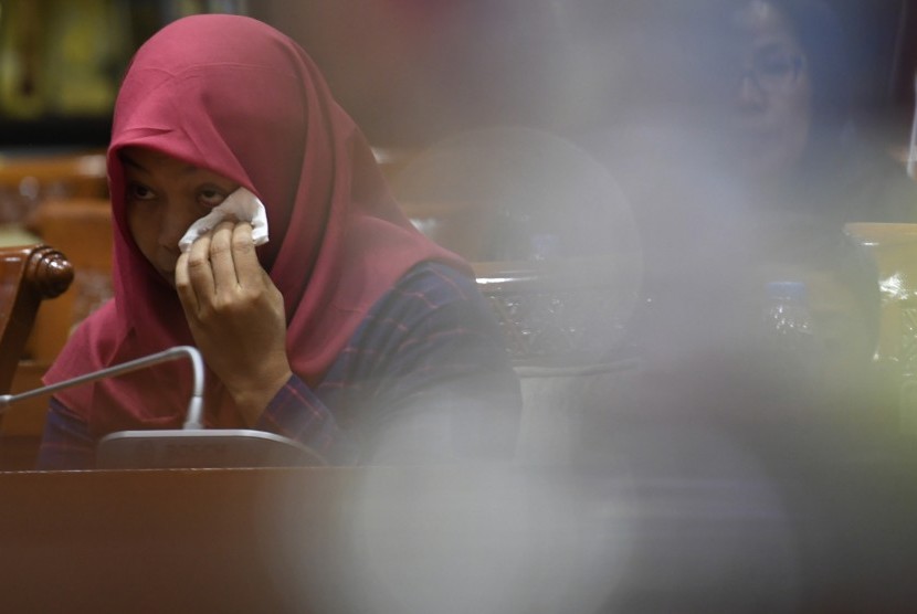 Terpidana kasus pelanggaran Undang-Undang Transaksi dan Informasi Elektronik (UU ITE), Baiq Nuril Maknun menyeka air mata saat mengikuti rapat pleno Komisi III DPR terkait surat persetujuan amnesti di Kompleks Parlemen Senayan, Jakarta, Selasa (23/7/2019). 