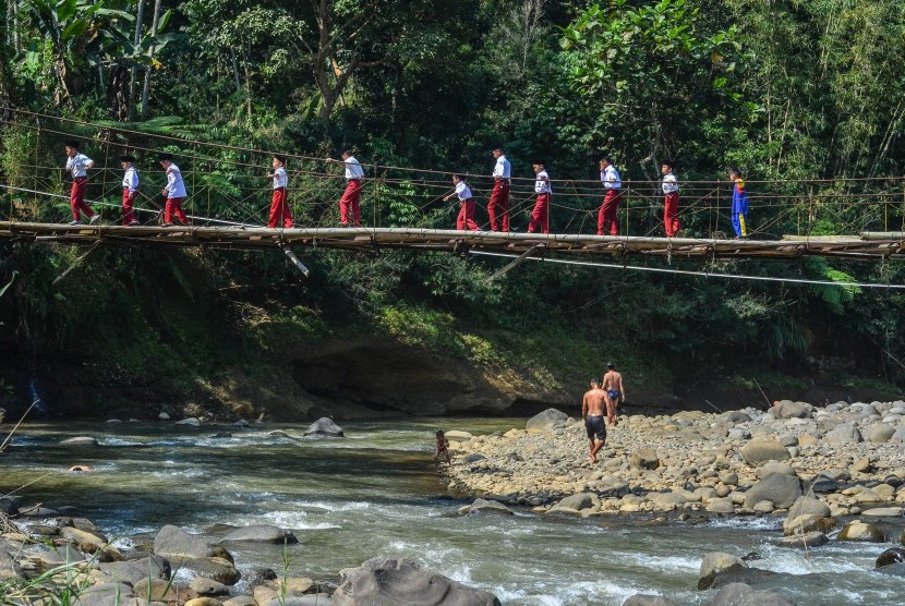 Siswa Sekolah Dasar (SD) menyeberangi Jembatan Gantung Lengkongjaya yang melintasi Sungai Ciwulan, Desa Pusparaja, Kabupaten Tasikmalaya, Jawa Barat, Selasa (23/7/2019). 