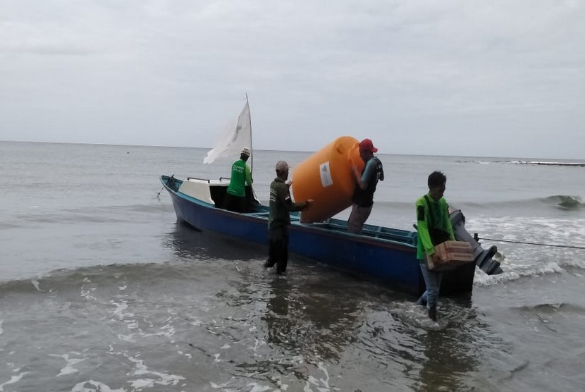 Tim Disaster Management Center (DMC) Dompet Dhuafa mendistribusikan bantuan tangki air melalui jalur laut di titik pengungsian korban gempa Gunung Lojong, Halmahera Selatan,  Maluku Utara.