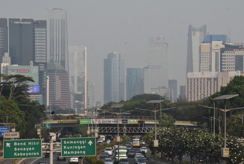 Kendaraan melintas dengan latar belakang gedung bertingkat yang tersamar polusi di kawasan Gatot Subroto, Jakarta, Ahad (28/7/2019). 