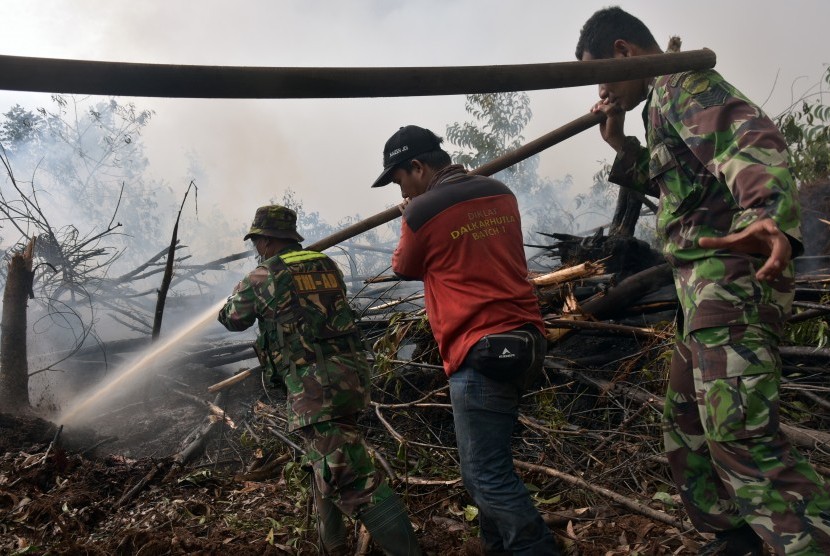 Sejumlah personel TNI Koramil 09 Langgam bersama pemadam kebakaran PT Riau Andalan Pulp and Paper (RAPP) berusaha memadamkan kebakaran lahan gambut di Desa Penarikan Kecamatan Langgam Kabupaten Pelalawan, Riau, Ahad (28/7/2019). 