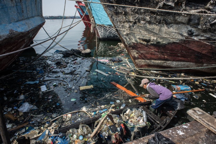 Pekerja membersihkan sampah yang terbawa arus di kawasan pesisir Muara Baru, Jakarta, Rabu (31/7/2019).