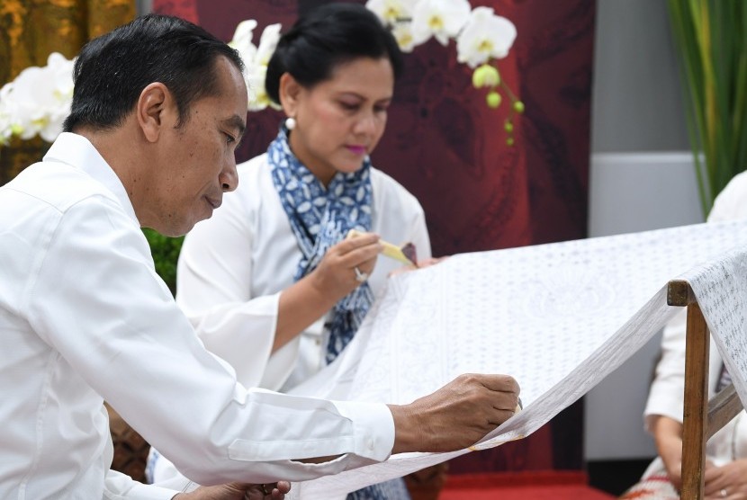 Presiden Joko Widodo (kiri) bersama Ibu Negara Iriana Joko Widodo (kanan) mencanting batik motif Gurdo di kain sepanjang 74 meter saat menghadiri kegiatan Batik Kemerdekaan di Stasiun MRT Bundaran HI Jakarta, Kamis (1/8/2019).