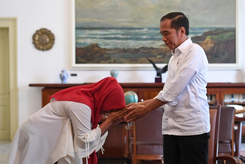 Presiden Joko Widodo (kanan) bersalaman dengan terpidana kasus pelanggaran Undang-Undang Informasi dan Transaksi Elektronik (ITE) Baiq Nuril Maknun di Istana Bogor, Jawa Barat, Jumat (2/8/2019).