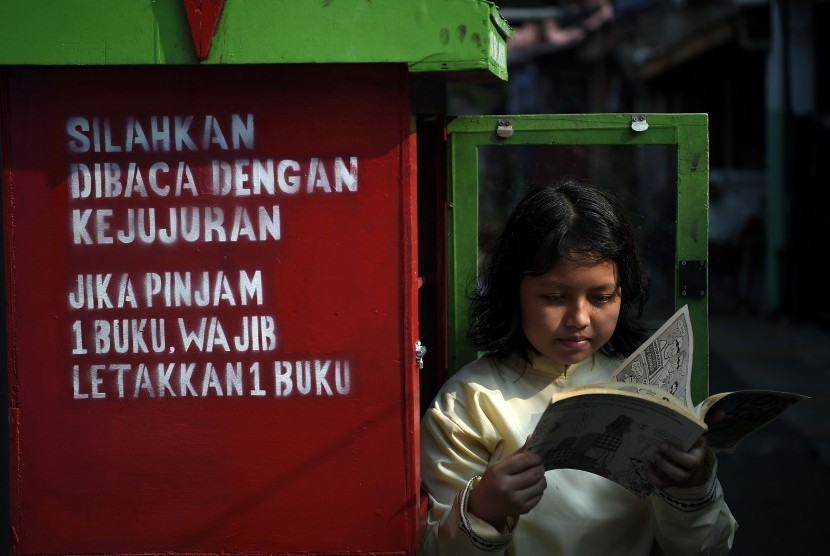 Seorang bocah membaca buku yang dipinjamkan secara gratis. Ilustrasi