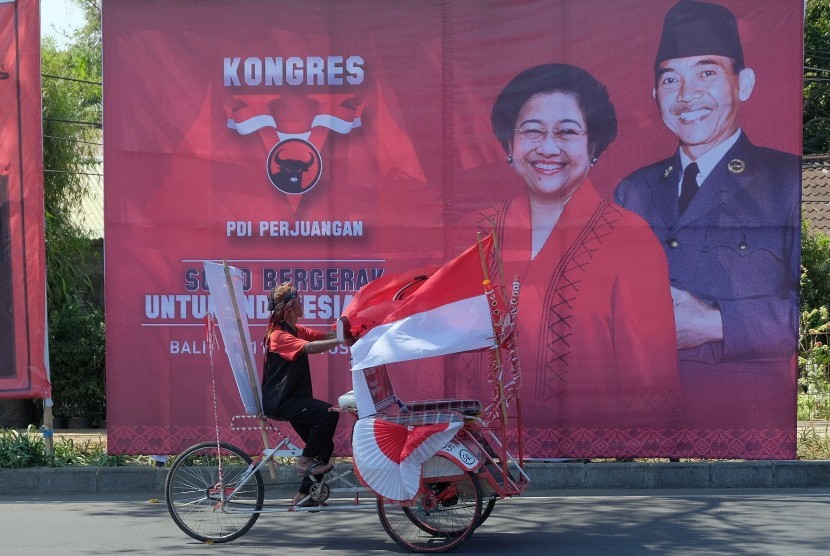 Simpatisan PDI Perjuangan mengayuh becak di dekat baliho Kongres V PDI Perjuangan di Denpasar, Bali, Selasa (6/8/2019).