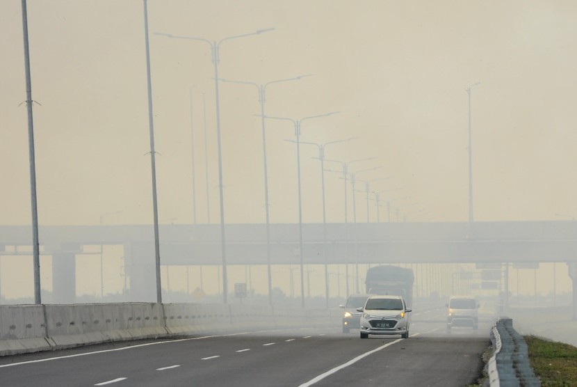 Kendaraan menerobos kabut asap akibat kebakaran lahan di tol Palembang-Indralaya, Sumatera Selatan, Rabu (7/8/2019).