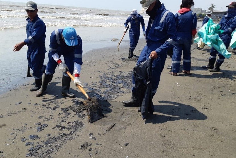 Petugas Pertamina dibantu warga, sedang membersihkan ceceran spill oil di Pantai Cemara, Desa Cemarajaya, Kecamatan Cibuaya, Rabu (7/8). Pencemaran limbah minyak ini, sudah terjadi hampir sebulan. 