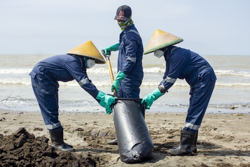 Petugas mengumpulkan tumpahan minyak mentah yang tercecer di Pesisir Pantai Mekarjaya, Karawang, Jawa Barat, Kamis (8/8/2019).