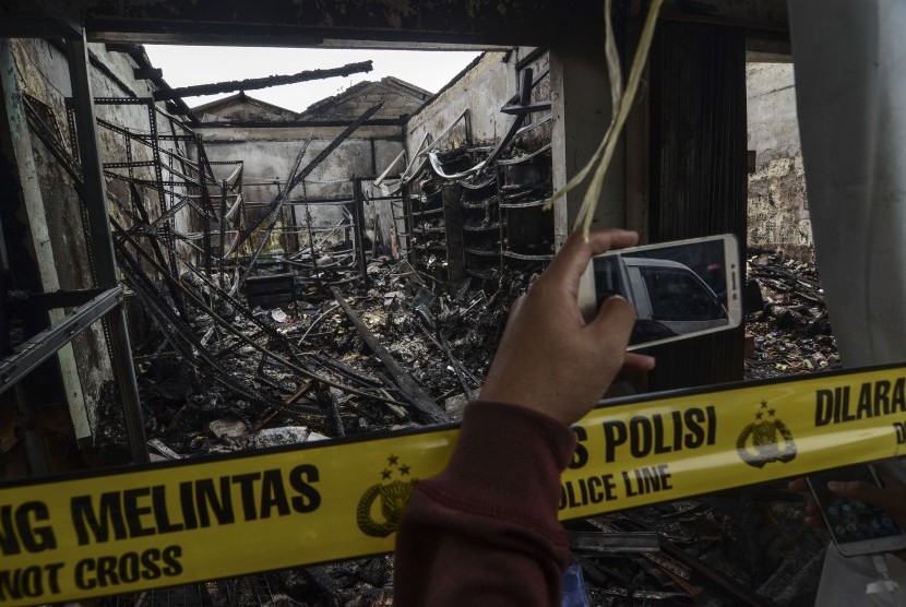 Jurnalis mengambil gambar sisa kebakaran ruko di daerah Cipayung,Jakarta Timur, Jumat (9/8/2019). 