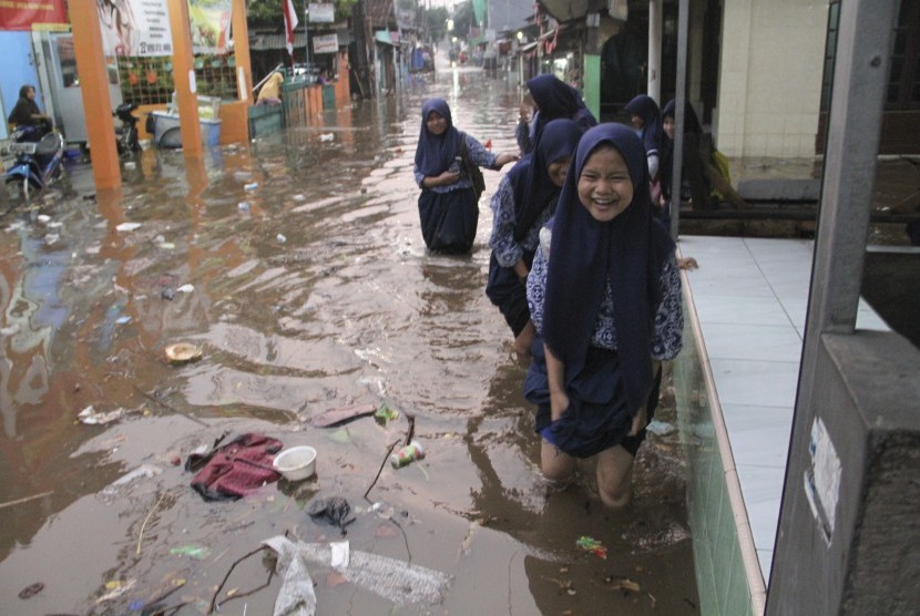 Korban banjir Depok mengungsi di masjid dan hotel. Foto: Sejumlah anak sekolah melintasi banjir di Depok, Jawa Barat, Kamis (15/8/2019).