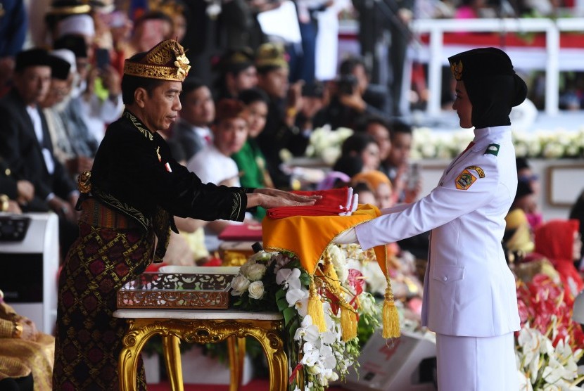 Presiden Joko Widodo (kanan) memberikan bendera kepada pembawa baki Paskibraka Salma El Mutafaqqiha Putri Achzaabi (kiri) dalam Upacara Peringatan Detik-Detik Proklamasi Kemerdekaan Indonesia ke-74 Tahun 2019 di Istana Merdeka, Jakarta, Sabtu (17/8/2019). 
