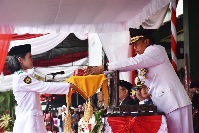 Wali Kota Yogyakarta, Haryadi Suyuti menyerahkan bendera  kepada pembawa bendera, Tsana Aqila U untuk dikibarkan pada upacara  peringatan kemerdekaan Indonesia ke 74 di Balai Kota Yogyakarta