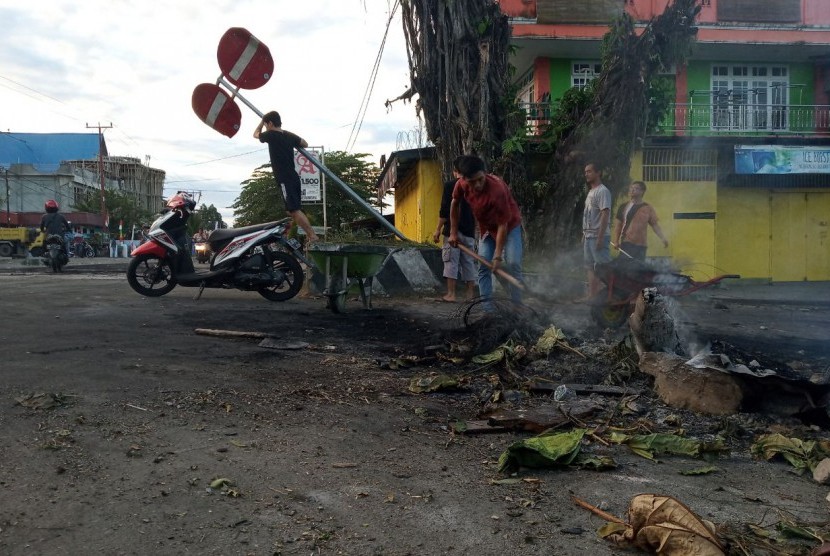 Warga membersihkan sisa ban yang dibakar seusai aksi di Jl.Essau Sesa Manokwari, Papua Barat, Senin (19/8/2019). 